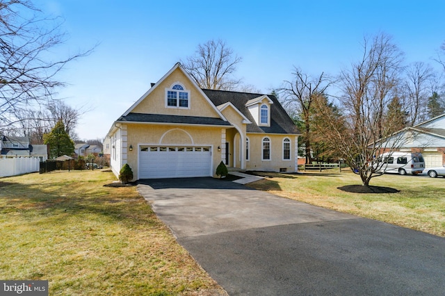 view of front of home featuring a front lawn, fence, a garage, and aphalt driveway