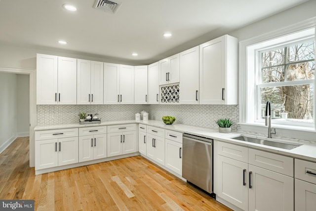 kitchen featuring tasteful backsplash, visible vents, stainless steel dishwasher, light wood-style floors, and a sink
