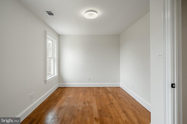 empty room featuring visible vents, baseboards, and wood finished floors