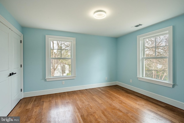 unfurnished bedroom featuring visible vents, baseboards, and wood finished floors