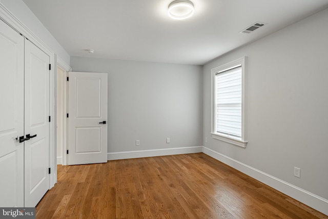 unfurnished bedroom with a closet, visible vents, baseboards, and light wood-style floors