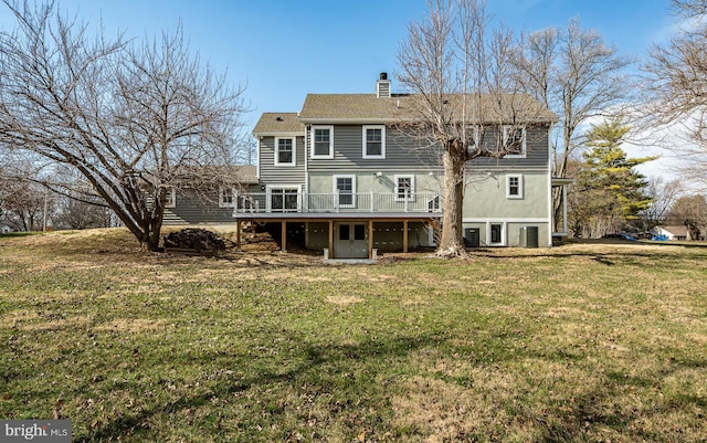 back of property with a wooden deck, a lawn, and a chimney