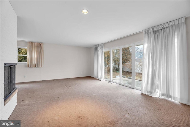 carpeted spare room with recessed lighting and a fireplace