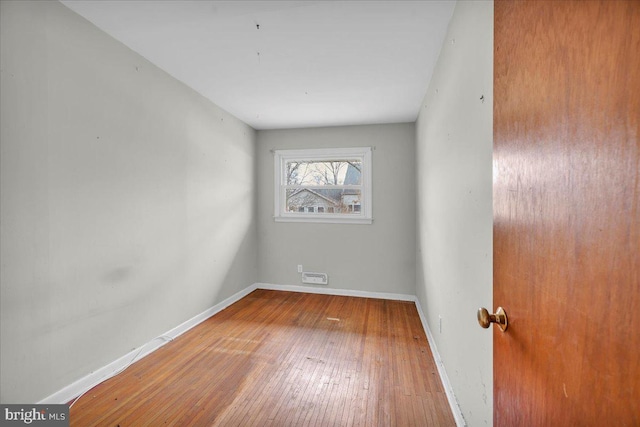 spare room featuring hardwood / wood-style flooring and baseboards