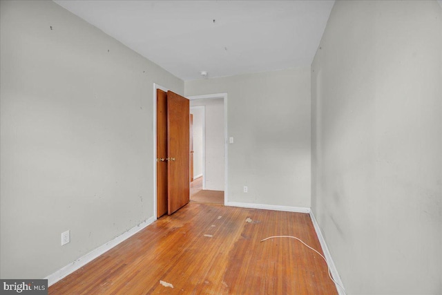 spare room featuring baseboards and hardwood / wood-style floors