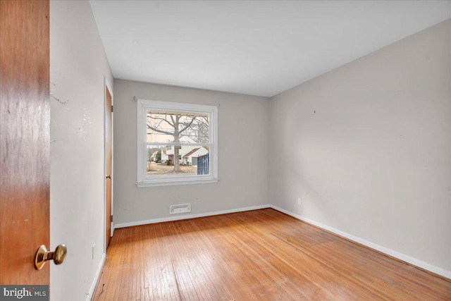 empty room featuring visible vents, baseboards, and wood-type flooring