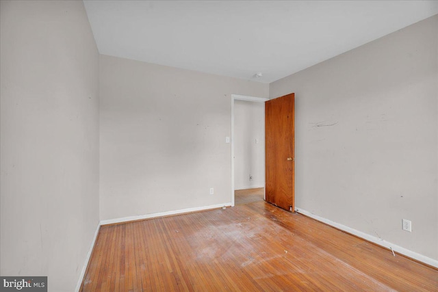 empty room featuring baseboards and wood-type flooring