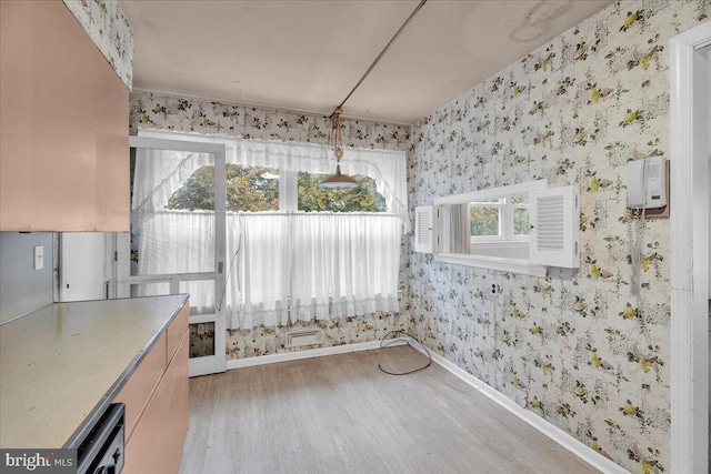 unfurnished dining area with wallpapered walls, wood finished floors, and baseboards