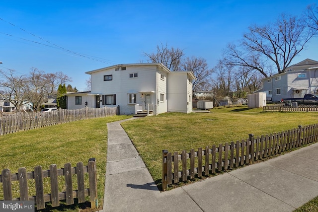 view of front of property with a fenced front yard, a front lawn, a storage shed, and an outdoor structure