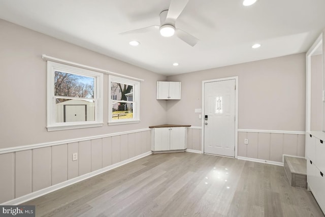 interior space with light wood finished floors, recessed lighting, wainscoting, and a ceiling fan