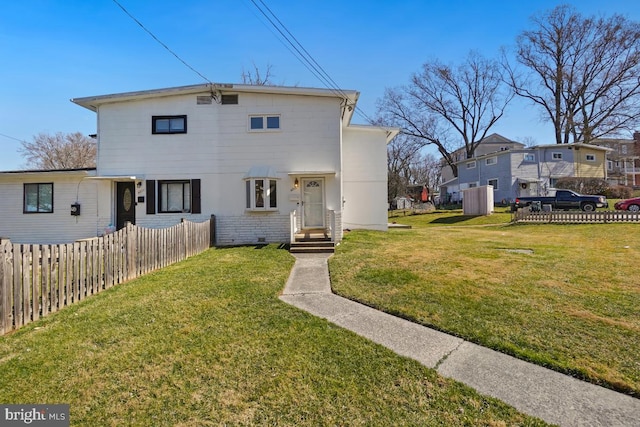 rear view of property featuring fence, brick siding, and a lawn