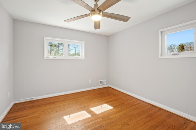 empty room featuring visible vents, ceiling fan, baseboards, and wood finished floors