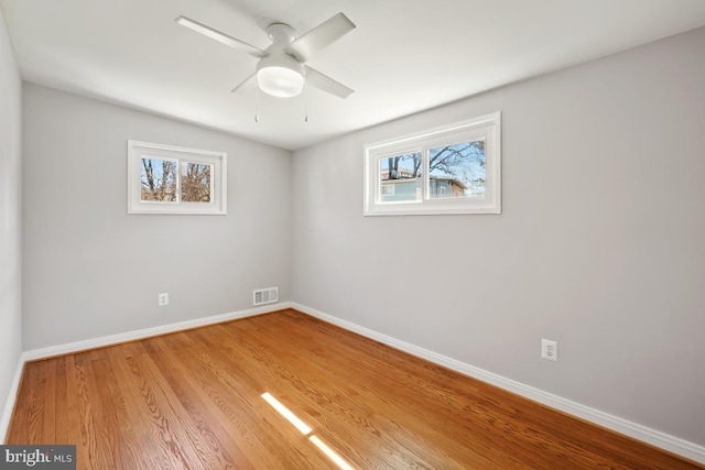 spare room with light wood-type flooring, visible vents, baseboards, and a healthy amount of sunlight