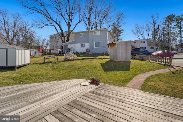 wooden deck with an outbuilding, fence, and a shed