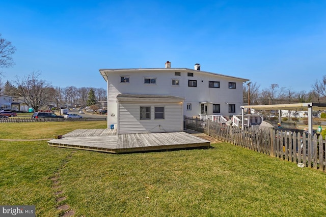 rear view of property with a wooden deck, a yard, and fence