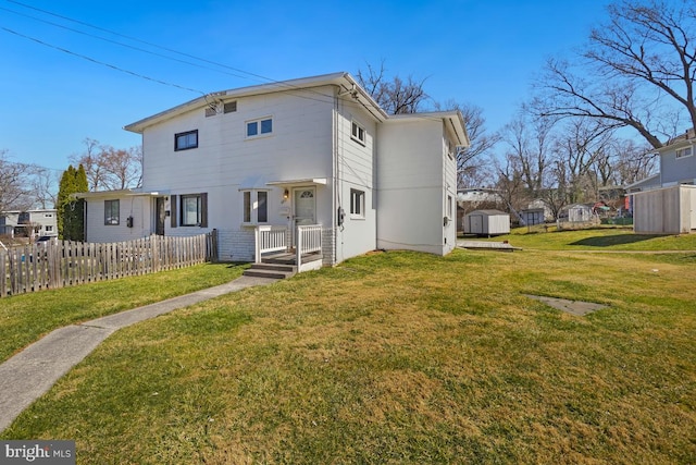 back of property with a storage unit, a yard, an outdoor structure, and fence