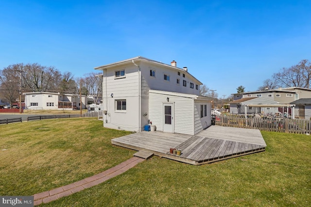 back of house featuring a wooden deck, a lawn, a chimney, and fence