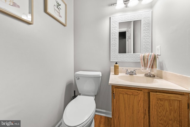 bathroom featuring vanity, toilet, wood finished floors, and baseboards