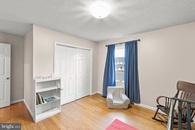 living area with baseboards, a textured ceiling, and hardwood / wood-style flooring