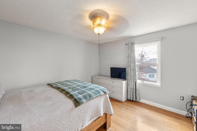 bedroom with light wood-style flooring, baseboards, and ceiling fan