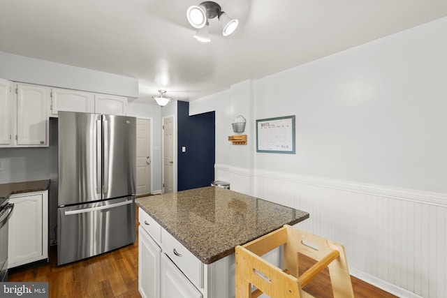 kitchen featuring a wainscoted wall, white cabinetry, freestanding refrigerator, and dark wood-type flooring