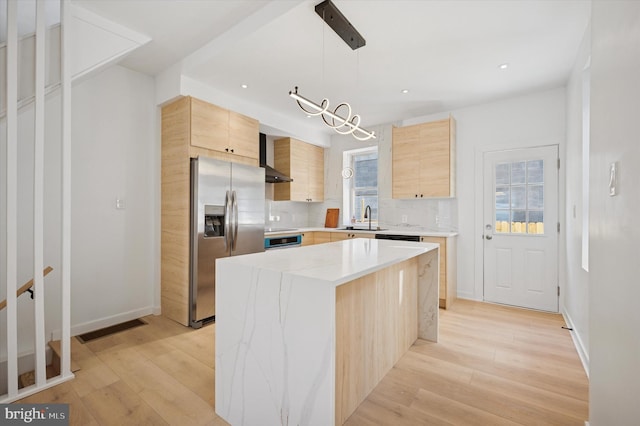 kitchen featuring stainless steel fridge with ice dispenser, light brown cabinetry, backsplash, a sink, and wall chimney range hood