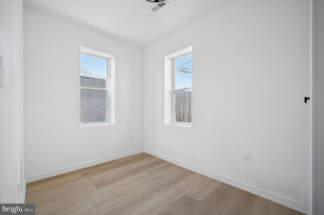 unfurnished room with plenty of natural light, baseboards, light wood-style floors, and visible vents