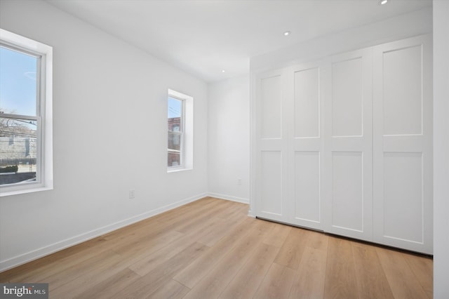 unfurnished bedroom featuring baseboards, a closet, recessed lighting, and light wood-type flooring