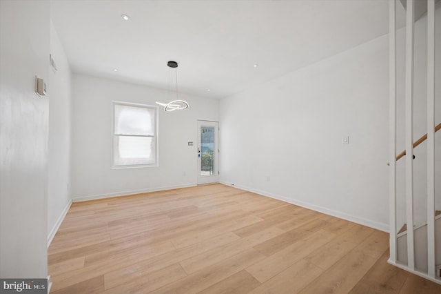 spare room featuring baseboards, stairway, light wood finished floors, and recessed lighting
