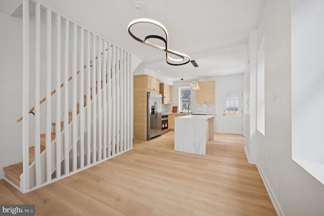 kitchen with light countertops, stainless steel appliances, light wood-type flooring, a center island, and light brown cabinetry