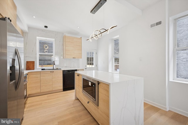 kitchen featuring visible vents, stainless steel fridge, black dishwasher, built in microwave, and light brown cabinetry