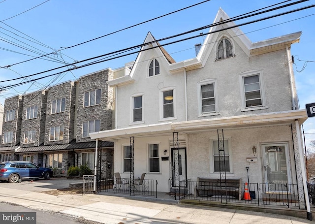 townhome / multi-family property featuring a fenced front yard, covered porch, and stucco siding