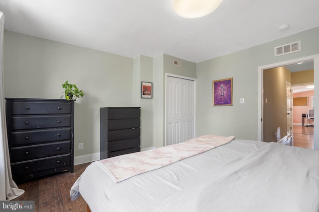 bedroom with dark wood-type flooring, baseboards, visible vents, and a closet