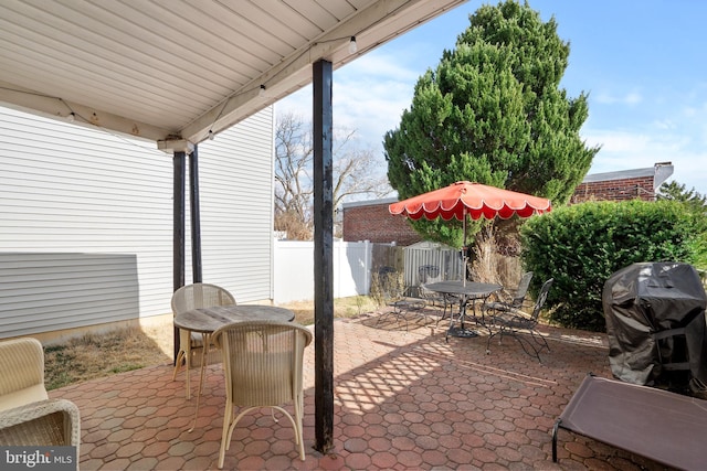 view of patio featuring outdoor dining area, a grill, and fence