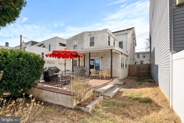 rear view of property with stucco siding, a patio, and fence