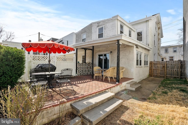 back of house with stucco siding, a patio area, and fence