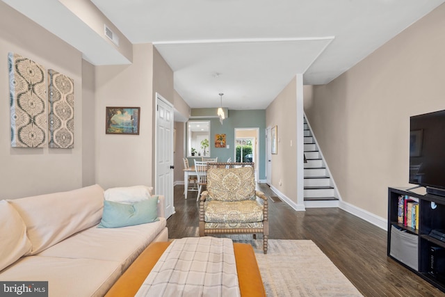 living room featuring visible vents, stairway, dark wood-type flooring, and baseboards