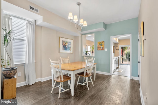 dining room with visible vents, an inviting chandelier, baseboards, and wood finished floors