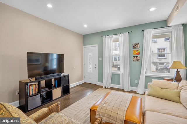 living room featuring visible vents, plenty of natural light, baseboards, and wood finished floors