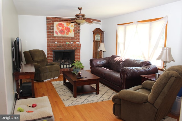 living room featuring a healthy amount of sunlight, a brick fireplace, light wood-style floors, and ceiling fan