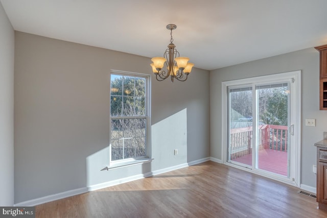 unfurnished dining area with visible vents, plenty of natural light, baseboards, and wood finished floors