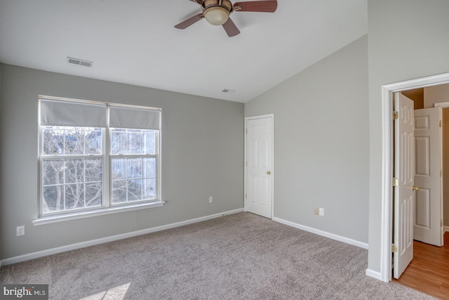 unfurnished bedroom featuring visible vents, carpet flooring, baseboards, and vaulted ceiling