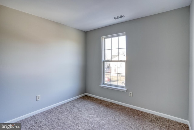 carpeted spare room featuring baseboards, visible vents, and a wealth of natural light