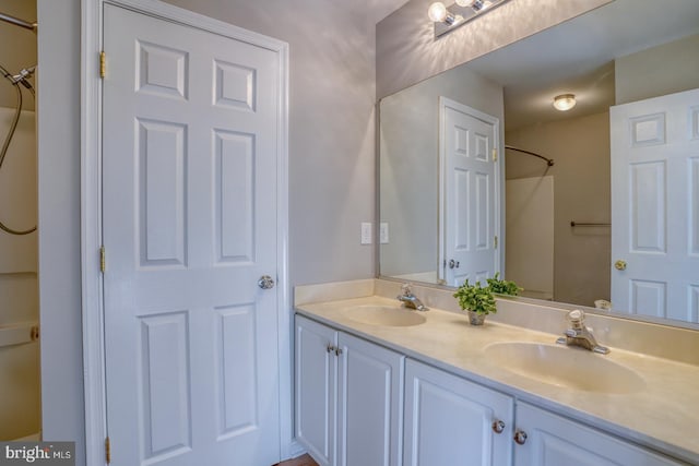 full bath featuring double vanity, a shower, and a sink