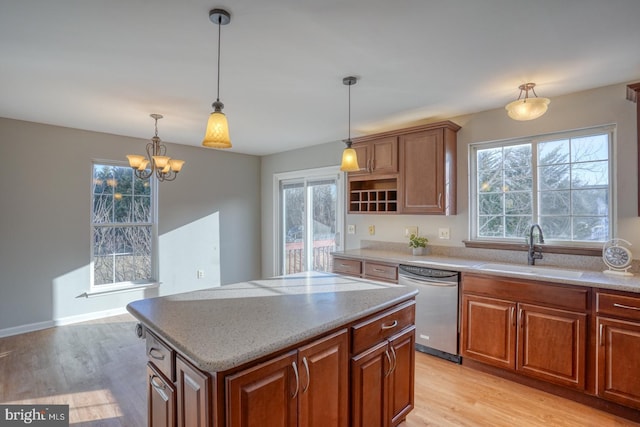 kitchen featuring a center island, dishwasher, light wood-type flooring, hanging light fixtures, and a sink