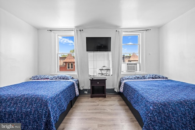 bedroom with cooling unit and wood finished floors