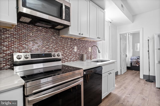 kitchen featuring visible vents, a sink, white cabinets, appliances with stainless steel finishes, and backsplash