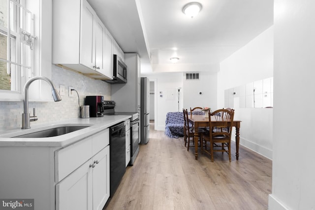 kitchen with visible vents, backsplash, light countertops, stainless steel appliances, and a sink