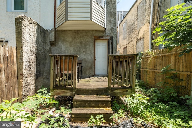 doorway to property featuring a deck, fence, and stucco siding