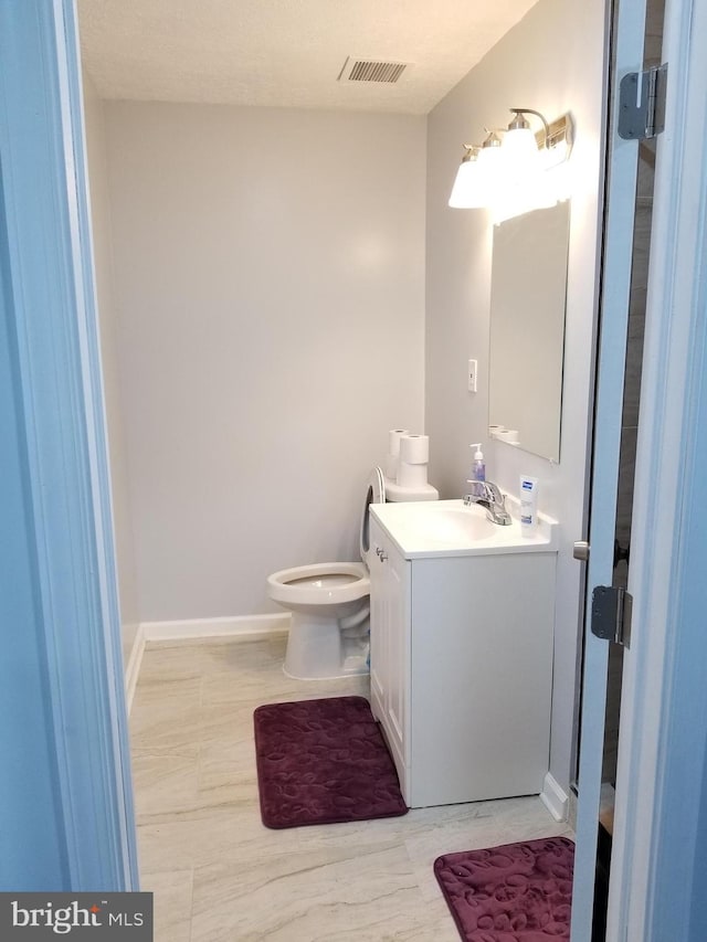 bathroom featuring visible vents, toilet, vanity, and baseboards